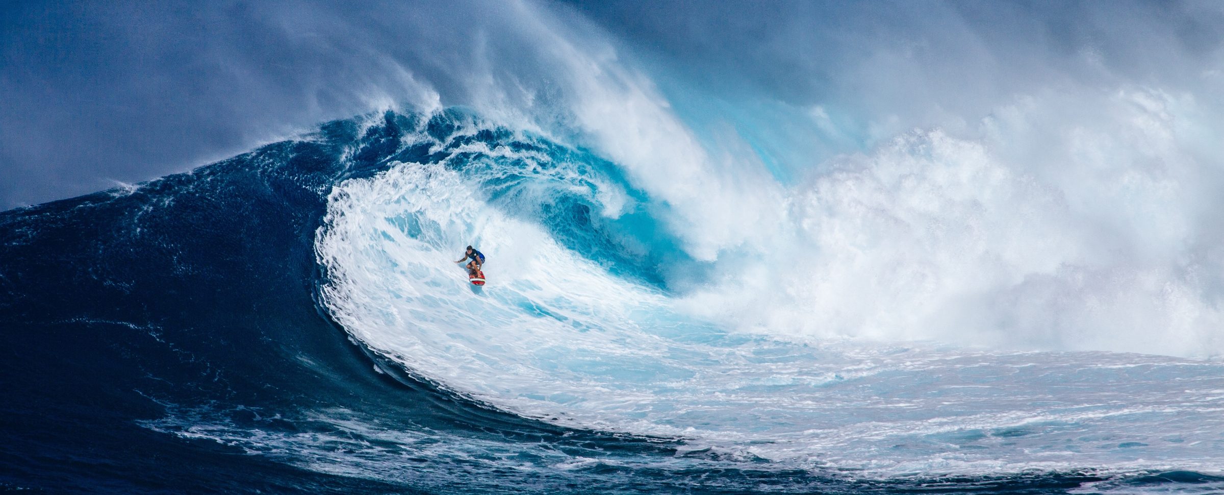 A surfer riding inside a huge breaking wave